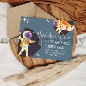 May include: A greeting card with an astronaut theme. The card features two astronauts and the text "Need More Space, I go to the moon & back for my clients! Give me a call for all of your real estate needs."