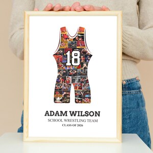 K&ouml;nnte beinhalten: Gerahmter Druck mit einem Wrestling-Singlet-Design, gef&uuml;llt mit Actionfotos. Das Singlet ist rot und schwarz mit der Nummer 18 in Wei&szlig;. Der Druck enth&auml;lt den Namen "ADAM WILSON", "SCHOOL WRESTLING TEAM" und "CLASS OF 2026".