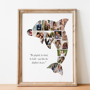 Op de afbeelding: Een witte ingelijste print met een collage van foto's in de vorm van een dolfijn. De quote "Wees speels, wees aardig, wees dapper - net als het hart van de dolfijn." staat onder de collage.