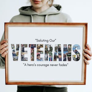 May include: A framed print with a brown wooden frame. The word "VETERANS" is spelled out in large letters, each filled with a collage of photos. The text "Saluting Our" and "A hero's courage never fades" are above and below the word.
