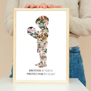 K&ouml;nnte beinhalten: Gerahmter Druck mit hellem Holzrahmen. Er zeigt eine Silhouette einer Person, die ein Baby h&auml;lt, zusammengesetzt aus vielen kleinen Fotos. Der Text "BROTHER BY BIRTH PROTECTOR BY HEART" befindet sich unten.