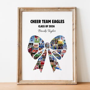 May include: Framed print featuring a bow-shaped collage of photos, with the text "CHEER TEAM EAGLES CLASS OF 2026" and a name. The frame is a light brown color, and the print is displayed on a wooden surface.
