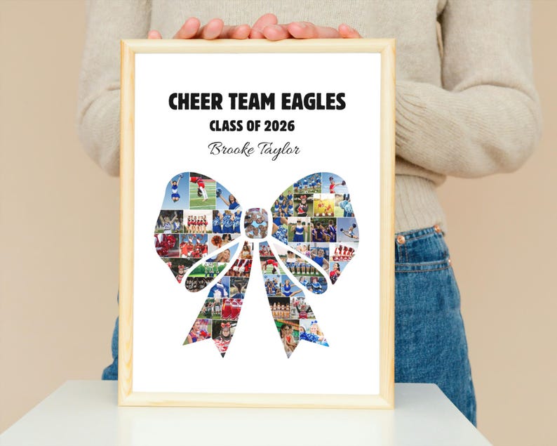 May include: A framed print with the text "CHEER TEAM EAGLES CLASS OF 2026" and the name "Brooke Taylor." The image features a bow-shaped collage of cheerleading photos. The frame is made of light-colored wood.