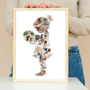 May include: A framed photo collage in the shape of a girl holding a heart. The heart and girl's silhouette are filled with multiple baby photos. The frame is light brown.