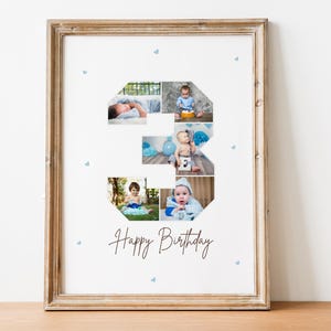 Op de afbeelding: Een fotocollage in de vorm van het cijfer 3, met een babyjongen in verschillende poses. De collage is afgedrukt op wit papier en ingelijst in een lichtbruin houten lijst. De tekst "Happy Birthday" is in bruin cursief onder de collage geschreven.