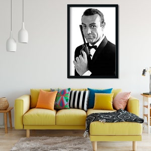 Peut inclure: Portrait en noir et blanc d'un homme en costume et nœud papillon tenant une arme à feu. L'image est encadrée en noir.