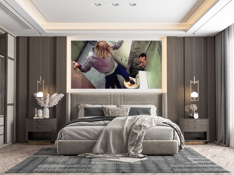 K&ouml;nnte beinhalten: Ein modernes Schlafzimmer mit einem grauen Kopfteil und einer grauen Bettdecke. Der Raum hat einen gro&szlig;en gerahmten Druck von zwei Personen in einem Badezimmer, einen grauen Teppich und zwei Nachttische mit Lampen.