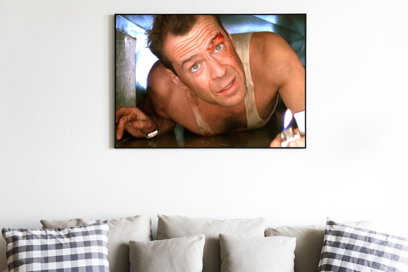 May include: A close-up of a man's face with a bloody cut on his forehead. He is wearing a white tank top and is holding a lighter with a flame. The image is from the movie "Die Hard with a Vengeance".