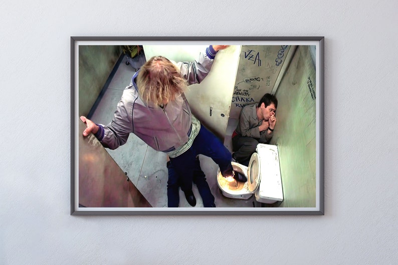 K&ouml;nnte beinhalten: Ein Mann in einer grauen Jacke und blauen Jeans steht &uuml;ber einem anderen Mann, der auf einer Toilette in einem Badezimmer sitzt. Der stehende Mann tritt mit seinem rechten Fu&szlig; auf die Toilette. Der Mann, der auf der Toilette sitzt, tr&auml;gt eine braune Jacke und hat seine H&auml;nde vor seinem Gesicht.