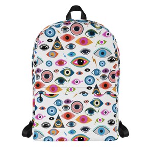 Puede incluir: Una mochila blanca con un patr&oacute;n de ojos coloridos. Los ojos son de varias formas y tama&ntilde;os, incluyendo c&iacute;rculos, &oacute;valos y tri&aacute;ngulos. Los colores incluyen azul, verde, rosa, naranja y amarillo.