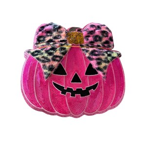 May include: A bright pink sequined pumpkin patch featuring a black felt jack-o'-lantern face with triangular eyes and a jagged mouth. A large bow with a pink, black, and tan leopard print pattern sits on top, accented by a small gold glitter center.