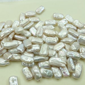 May include: A collection of white baroque pearls, each with an irregular, elongated shape. The pearls are smooth and lustrous, with a slightly iridescent sheen.