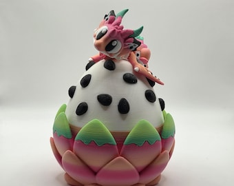 May include: A whimsical, colorful sculpture of a dragon fruit. The white fruit has black seeds and is topped with a pink and orange dragon figurine. The base is a pink, green, and orange lotus flower. A unique, decorative piece.