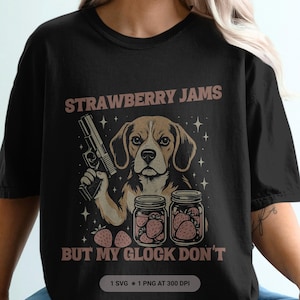 May include: Black t-shirt with a graphic of a beagle holding a gun, jars of strawberry jam, and the text "STRAWBERRY JAMS BUT MY GLOCK DON'T". The design includes stars and strawberries.