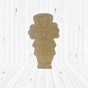May include: A brown paper cutout of a nutcracker with a black outline. The nutcracker has a tall hat, a mustache, and a smiling face. There are three black circles on the front of the nutcracker's uniform.