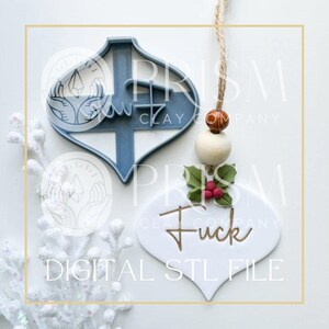 Peut inclure: Un emporte-pi&egrave;ce en argile en forme de d&eacute;coration de No&euml;l bleu et blanc et une d&eacute;coration finie avec le mot "Fuck" en script dor&eacute;. L'ornement a un ornement de houx et de baies et une ficelle pour l'accrocher. Le texte "DIGITAL STL FILE" est en bas.