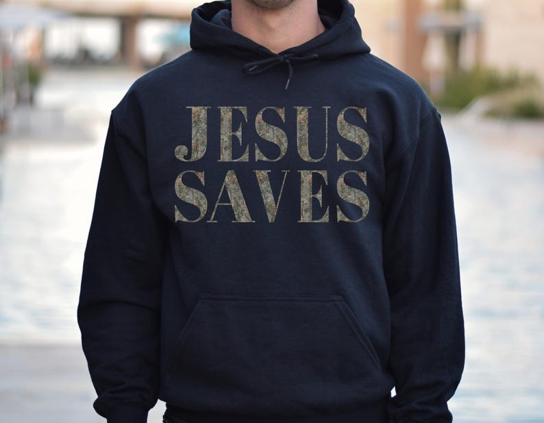 Puede incluir: Una sudadera con capucha azul oscuro con las palabras "JESUS SAVES" impresas en un patr&oacute;n de camuflaje en la parte delantera.