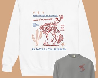 Può includere: Felpa a maniche lunghe bianca e grigia con una stampa grafica di un cowboy che cavalca un cavallo imbizzarrito. La grafica include il testo "Our Father in Heaven, hallowed be your name, Your Kingdom Come, Your Will Be Done, On Earth As It Is In Heaven."