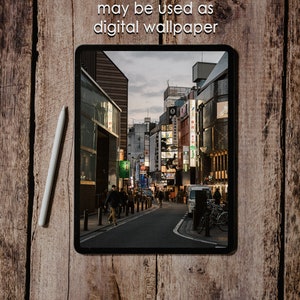 May include: A digital tablet displaying a photo of a street in a city with buildings and people walking. The text "may be used as digital wallpaper" is displayed above the tablet.