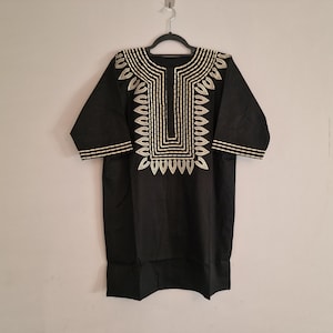 May include: A black short-sleeved shirt with a gold embroidered design around the neckline.