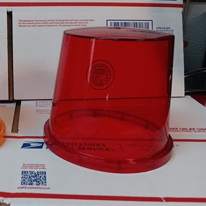 May include: Two red plastic mailboxes with the text "UNITED STATES POSTAL SERVICE" printed on the bottom. The mailboxes are on a white surface with a barcode and the text "USPS.COM/PICKUP".