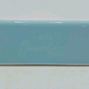 May include: A rectangular, light blue ceramic tile with a glossy finish. The tile has rounded edges and a smooth surface, suitable for use in bathrooms or kitchens.