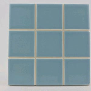 May include: A square of nine light blue ceramic tiles with a glossy finish. The tiles are arranged in a 3x3 grid, separated by thin, off-white grout lines. The tiles are a solid, muted blue color.