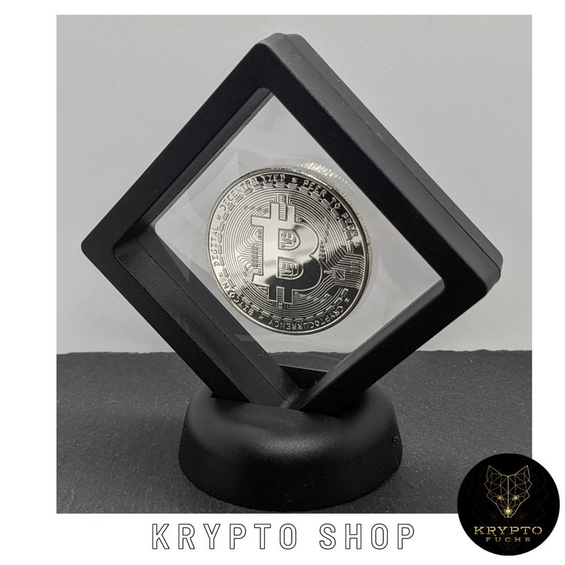 May include: A silver-colored Bitcoin coin is displayed in a black acrylic display case with a black base. The coin features the Bitcoin logo and the words "Digital Decentralized Peer to Peer."