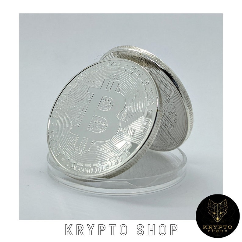 May include: Two silver-colored Bitcoin coins with the Bitcoin symbol on one side and text on the other side. The coins are stacked on top of each other.