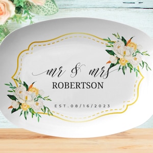 May include: White oval serving platter with a gold frame and floral design. The text "Mr. & Mrs. Robertson Est. 08/16/2023" is printed on the platter.