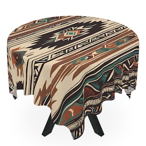 May include: Round tablecloth with a Southwestern-inspired design. The tablecloth features a cream background with geometric patterns in shades of brown, black, teal, and orange. The tablecloth is draped over a black table.