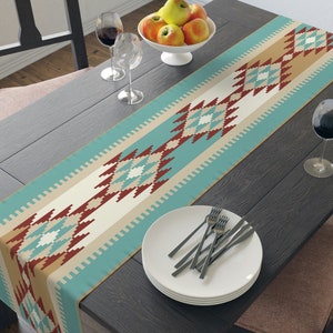 May include: A turquoise, beige, and red geometric patterned table runner with a diamond design. The runner is on a dark wood table with a plate and silverware.