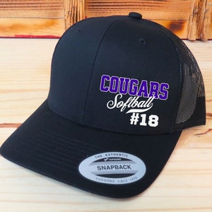 May include: Black and purple mesh baseball cap with the text "Cougar Softball #18" on the front. The cap has a black brim and a black mesh back.