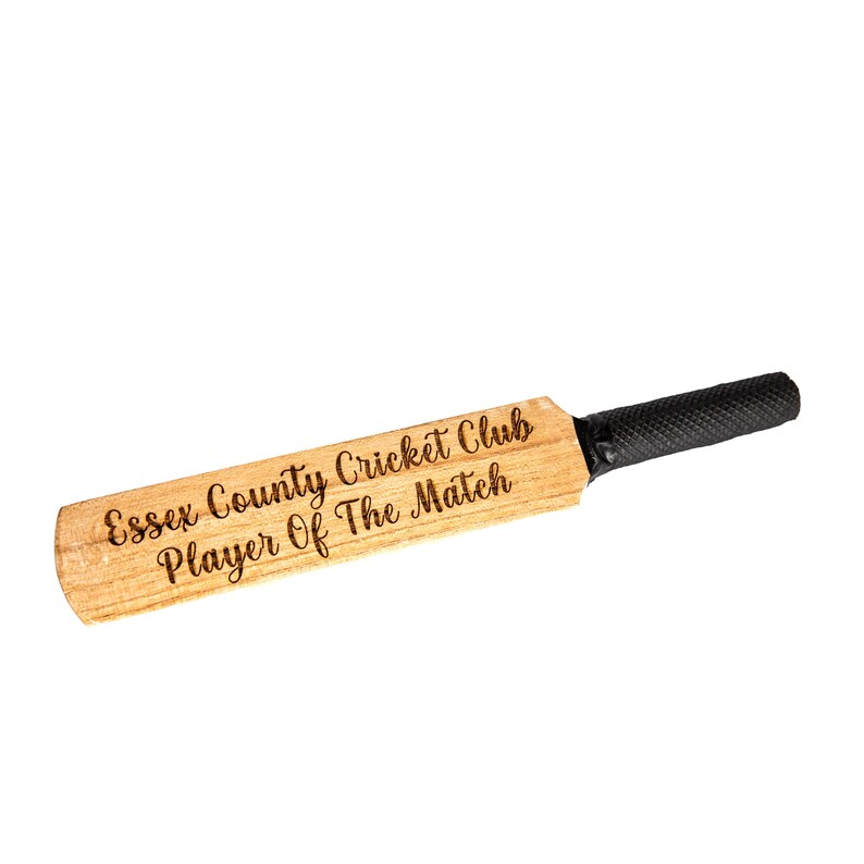 May include: A wooden cricket bat with a black grip. The bat has the text "Essex County Cricket Club Player Of The Match" engraved on the wood.