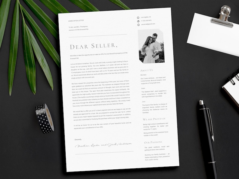 May include: A home offer letter on white paper with the text "Dear Seller," and a black and white photo of a couple. A black pen, a notepad, and a silver clip are also on the black surface. Green leaves and black and white polka dot tape are in the background.