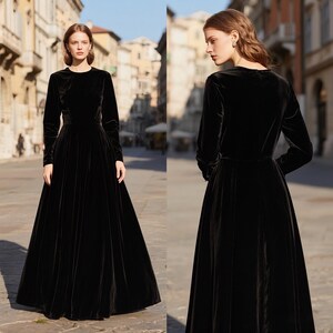Puede incluir: Un vestido largo de terciopelo negro con mangas largas y falda hasta el suelo. El vestido tiene un dise&ntilde;o sencillo y elegante, ideal para eventos formales. La modelo se encuentra en un entorno exterior, mostrando la silueta fluida del vestido.