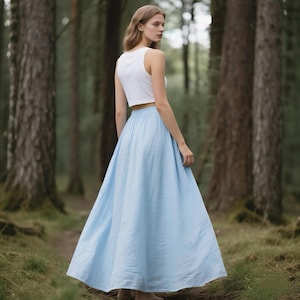 May include: A white sleeveless crop top paired with a light blue floor-length maxi skirt. The skirt features a gathered elasticated waistband and a full, flowing silhouette that reaches the ground, crafted from a solid-coloured fabric.