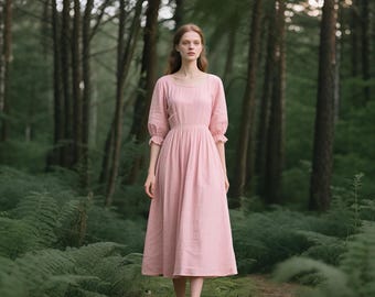 May include: A light pink midi dress with a round neckline and elbow-length sleeves. The dress has a fitted waist and a flowing skirt. The woman is standing barefoot in a forest with tall trees and green foliage.