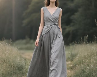 May include: A floor-length grey sleeveless dress featuring a V-neckline and a wrap-style bodice with a side tie closure at the waist. The garment has a full, flowing skirt that reaches the ground, constructed from a solid-colored fabric.