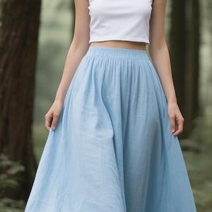 May include: A white sleeveless crop top paired with a light blue floor-length maxi skirt. The top features a scoop neckline and a fitted silhouette, while the skirt has a gathered elastic waistband and a full, flowing cut that reaches the ground.