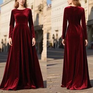 May include: A long, burgundy velvet dress with a round neckline and long sleeves. The dress has a flowing A-line skirt and is floor-length. The fabric has a soft sheen, and the dress appears to be well-tailored. The background shows a city street.