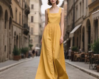 May include: A woman wearing a long, yellow, sleeveless linen dress with a square neckline. The dress has a fitted bodice and a flowing skirt.