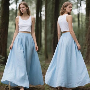 May include: A white sleeveless crop top paired with a light blue high-waisted maxi skirt. The skirt features a gathered elastic waistband and a full, flowing silhouette that reaches the ankles, while the top has a simple scoop neckline.