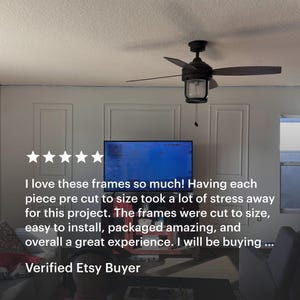 A room with white wall molding kit . The walls feature decorative rectangular frames. A television is mounted on the wall. Text on the image reads: "I love these frames so much!" and "Verified Etsy Buyer."