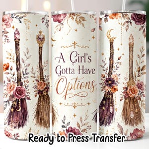May include: A cylindrical tumbler featuring a cream background with a floral and witchy theme. The design includes four broomsticks adorned with crystals, flowers, and moons, alongside the text "A Girl's Gotta Have Options" and "Ready to Press Transfer".