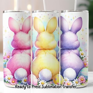 May include: Three white tumblers with Easter bunny designs in pink, yellow, and purple. Each tumbler features a fluffy bunny, Easter eggs, and flowers. The text "Ready to Press Sublimation Transfer" is at the bottom.