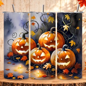 Op de afbeelding: Een cilindervormige beker met een metalen rietje met een Halloween-ontwerp van drie uitgesneden oranje pompoenen, donkere kronkelende ranken en verspreide gele en oranje herfstbladeren tegen een donkere achtergrond in aquarel.