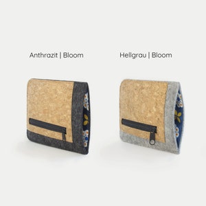 Puede incluir: Dos estuches con cremallera de corcho y fieltro con forro de estampado floral. El estuche de la izquierda es gris y el estuche de la derecha es gris claro. El texto "Anthrazit | Bloom" est&aacute; por encima del estuche de la izquierda y el texto "Hellgrau | Bloom" est&aacute; por encima del estuche de la derecha.