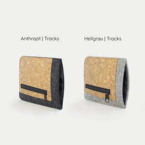Puede incluir: Dos estuches con cremallera de corcho y fieltro, uno en gris oscuro y otro en gris claro. El texto "Anthrazit | Tracks" est&aacute; sobre el estuche gris oscuro y el texto "Hellgrau | Tracks" est&aacute; sobre el estuche gris claro.