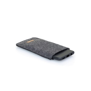 May include: A gray felt phone case with a brown leather patch. The case is designed to protect a smartphone.
